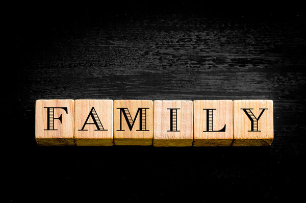 Word Familiy. Wooden small cubes with letters isolated on black background.Concept image.