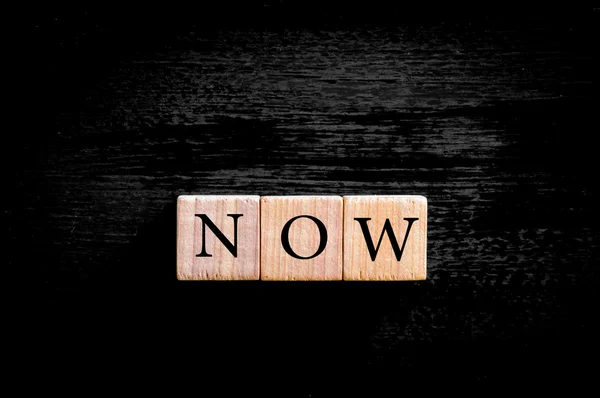 Word NOW isolated on black background with copy space — Stock Photo, Image