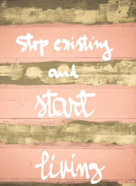 Imagem de conceito de Stop Existing e começar a viver citação motivacional mão escrita na parede de madeira pintada vintage — Fotografia de Stock