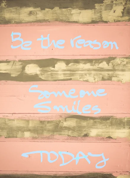 Concept image of Be the Reason someone smiles today motivational quote hand written on vintage painted wooden wall — Stock Photo, Image