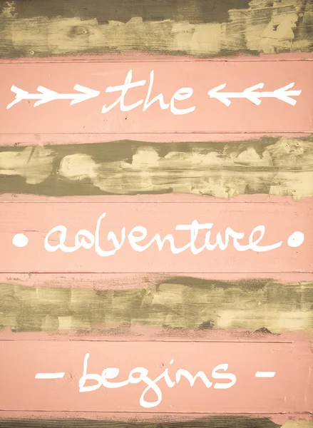 Begreppet bilden av The Adventure Begins motiverande citat handskriven på vintage målad trävägg — Stockfoto