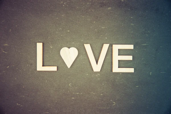 Word LOVE створений з дерев'яних літер над старовинною крейдою, літера O замінена дерев'яною формою серця — стокове фото