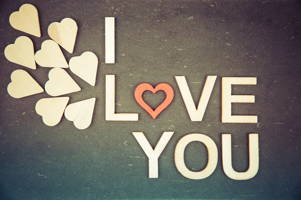 Words I LOVE YOU created of wood letters over vintage chalkboard, retro filter applied — Stock Photo, Image