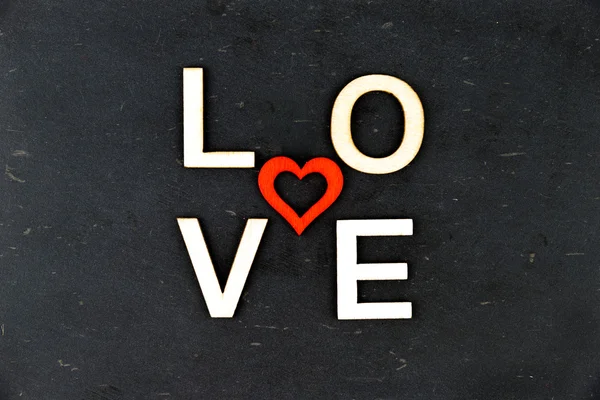 Слово ЛЮБОВЬ, созданное из деревянных букв, красное деревянное сердце в середине, изолированное на черном — стоковое фото