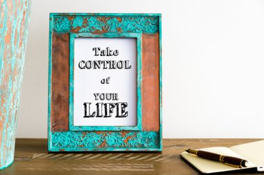Vintage photo frame on wooden table with text TAKE CONTROL OF YOUR LIFE