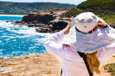 Young woman with hat looking away, ocean background 