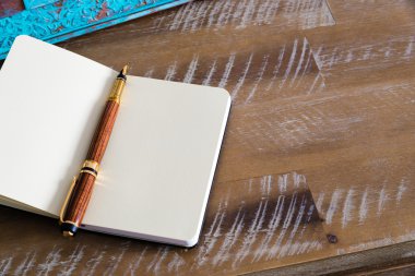 Classic fountain pen and open notebook on wooden table 