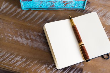 Classic fountain pen and open notebook on wooden table 