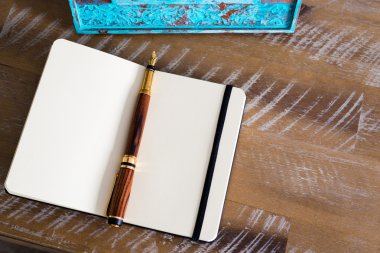 Classic fountain pen and open notebook on wooden table 