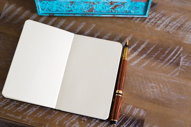 Classic fountain pen and open notebook on wooden table 