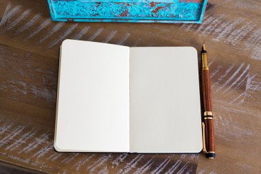 Classic fountain pen and open notebook on wooden table 