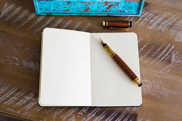 Classic fountain pen and open notebook on wooden table — 图库照片