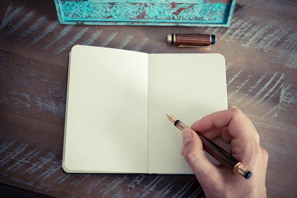 Retro effect en afgezwakt beeld van een vrouw hand schrijven een notitie met een vulpen op een notebook. — Stockfoto