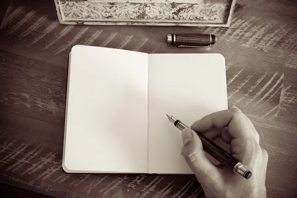 Efeito retrô e imagem tonificada de uma mulher mão escrevendo uma nota com uma caneta-tinteiro em um caderno . — Fotografia de Stock