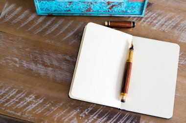 Classic fountain pen and open notebook on wooden table 