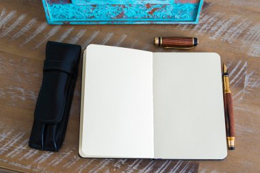 Classic fountain pen and open notebook on wooden table 