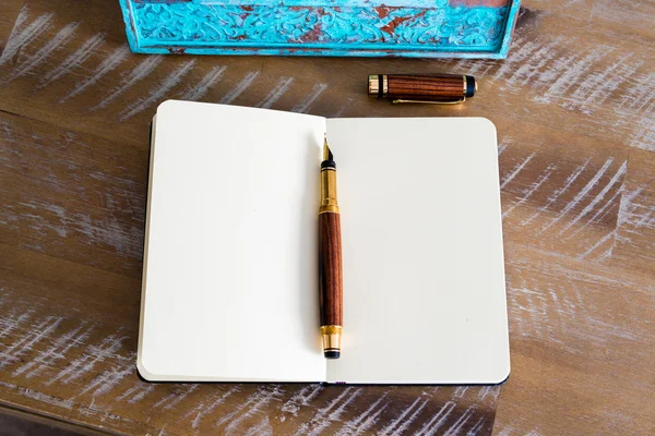 Caneta-tinteiro clássica e caderno aberto na mesa de madeira — Fotografia de Stock