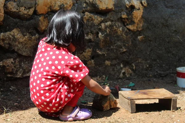 Seçici odak, kırmızı benekli elbise giyen Asyalı küçük bir kızın koyu bulanık arka planda oynaması. İçerik renklilik gürültüsü, parlaklık sesi, keskinleştirme sesi veya film içerir 