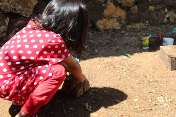Seçici odak, kırmızı benekli elbise giyen Asyalı küçük bir kızın koyu bulanık arka planda oynaması. İçerik renklilik gürültüsü, parlaklık sesi, keskinleştirme sesi veya film içerir 