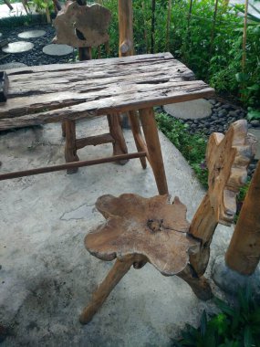 Ahşap bir masa ve ahşaptan yapılmış gri beton zemin zeminli eşsiz sandalyeler. Doğal mobilya kavramı