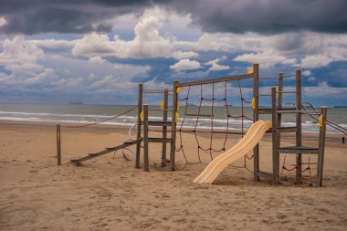 Hollanda Katwijk plajındaki küçük çocuklar için plastik kaydırak. Ufukta kruvazörler ve tankerler var.
