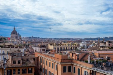 ROME, İtalya 18 Ocak 2026 Pincian Tepesi yakınlarındaki kaldırım taşı caddesinde antik bir dikilitaş yükselirken, yayalar park halindeki arabaların önünden geçerken, İtalya ve AB bayrakları mavi bir kış gökyüzüne doğru dalgalanıyor.