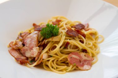 Pastırmalı spagetti, maydanoz ve parmesan peyniri taze biber, fesleğen yaprağı. Beyaz tabakta Carbonara makarnası. İtalyan gıda konsepti.