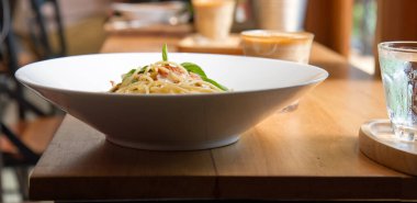 Pastırmalı spagetti, maydanoz ve parmesan peyniri taze biber, fesleğen yaprağı. Beyaz tabakta Carbonara makarnası. İtalyan gıda konsepti.