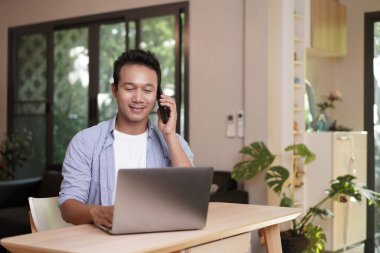 Evden çalışıyorum. Bilgisayarda çalışan Asyalı adam. Bilgisayarda internet üzerinden podcast izlemek öğrenim kursu konferansını dinlemek notlar almak çalışma masasına oturmak, konsept edinmek.