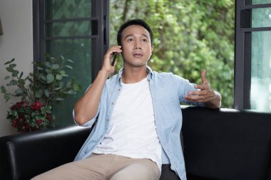 Evden çalışıyorum. Bilgisayarda çalışan Asyalı adam. Bilgisayarda internet üzerinden podcast izlemek öğrenim kursu konferansını dinlemek notlar almak çalışma masasına oturmak, konsept edinmek.