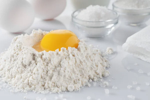 flour, egg yolk, salt, sugar, milk on a white table. baking ingredients