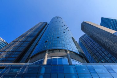 Yüksek katlı bir binanın ön cephesine bakın. Frankfurt 'taki bir gökdelenin cam cephesi. Mavi gökyüzü ve güneş ışığı ile finans ve iş bölgesinden gökdelen