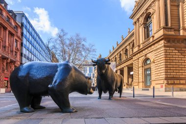 Frankfurt Borsası 'nın girişinin önünde. Boğa ve ayı bir sembol figürü. Ticari binalar, güneş ışığında kahverengi bir cephe ve baharda bulutlu mavi gökyüzü.