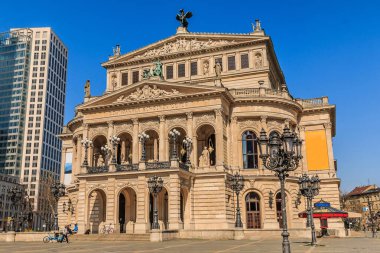 Eski Frankfurt Operası şehir merkezinde. İlkbaharda gün ışığında tarihi bina. Binanın önünde boş alan olan sokak lambaları. Arka planda iş binaları