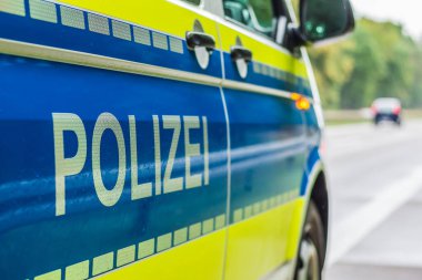 Otoyoldaki polis arabasının yolcu koltuğunun yan perspektifi. Bum ve sarı arka planı olan cesedin üzerine polis yerleştirmek. Arka planda sert omuz, şerit ve araba var.