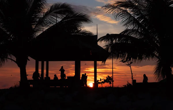 人们在热带日落天空中相遇的轮廓 免版税图库照片