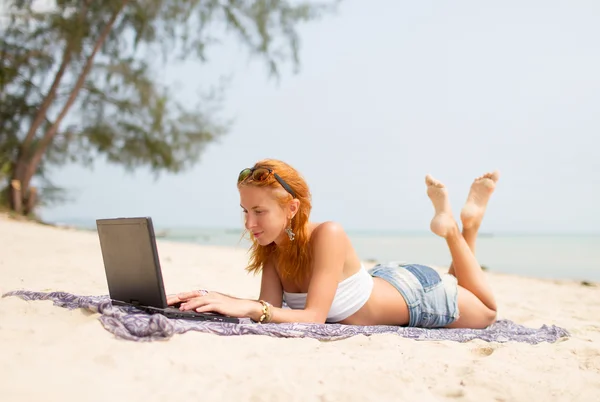 Girl working on the beach in a laptop — Stock Photo, Image