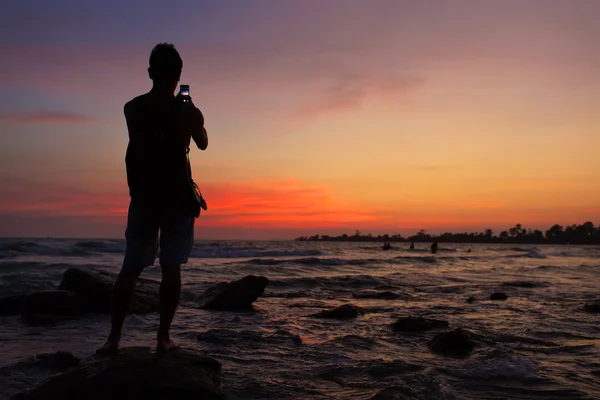 Silhueta de um homem o que foto nascer do sol no telefone — Fotografia de Stock