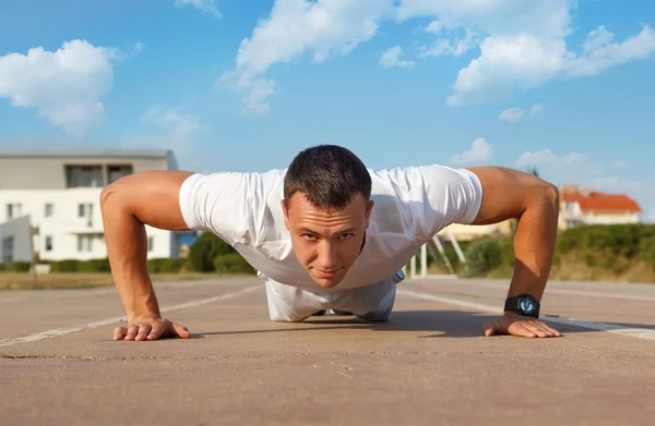 Athlete doing squeezing at the stadium — Stock Photo, Image