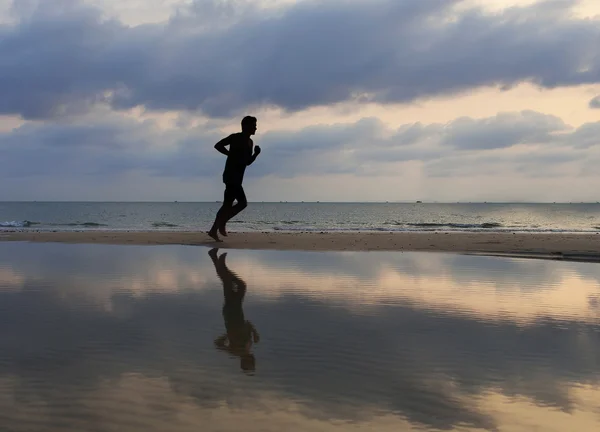 Αθλητής τρέχει κατά μήκος της παραλίας άμμου με καθρέφτη για το νερό και ο — Φωτογραφία Αρχείου