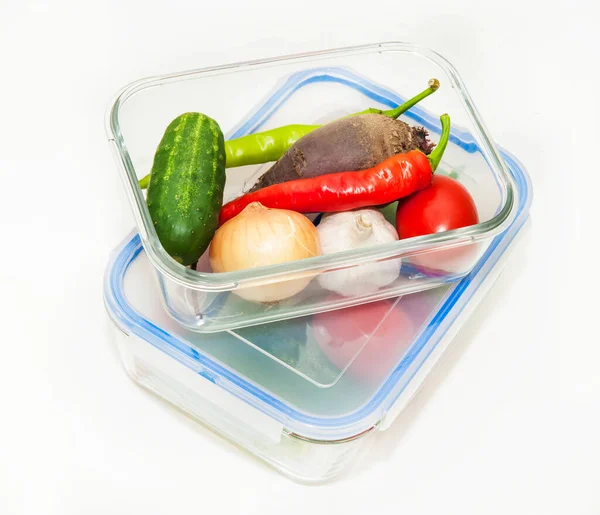 Glass food containers with vegetables on white background