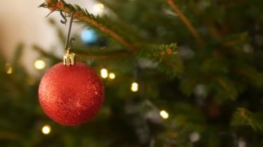 Bir Noel ağacının dallarında kırmızı pullu bir topun yakın çekimi.
