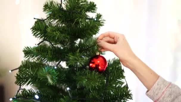 Primer plano de las manos femeninas decorando un hermoso árbol de Navidad. — Vídeos de Stock