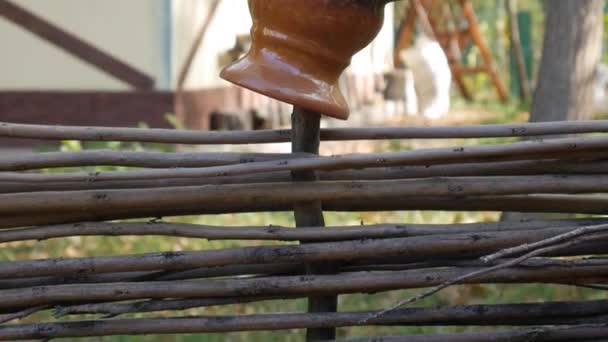 Глиняний глечик на дерев'яному паркані на тлі будинку у дворі . — стокове відео