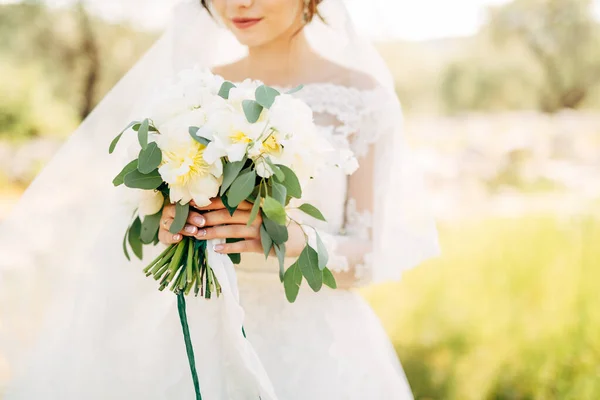 Bella sposa in abito da sposa tenero tenendo bouquet da sposa nelle sue mani — Foto Stock