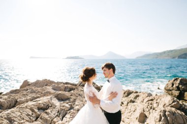 Gelin ve damat, Arza Kalesi yakınlarındaki Mamula adasının kayalık sahilinde kucaklaşıyorlar.