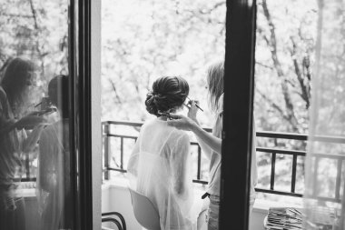 Makyaj sanatçısı tören hazırlıkları sırasında geline makyaj yapar.