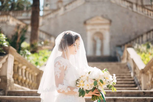 Bella sposa coperta da un velo con bouquet da sposa sulle scale della Natività della chiesa della Beata Vergine Maria a Prcanj — Foto Stock