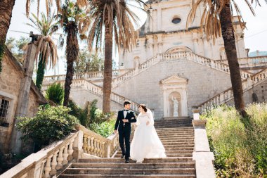 Gelin ve damat el ele tutuşun ve Prcanj 'daki Kutsal Bakire Meryem Kilisesi' nin merdivenlerinden aşağı inin.