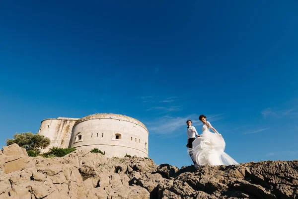 Brud och brudgum står tillsammans och håller händer nära Arza fästning på Mamula ön — Stockfoto